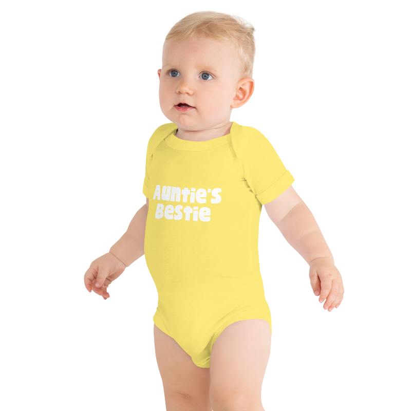 Baby wearing a yellow onesie with white 'Auntie's Bestie' text, on plain background, by Less Hustle, More Joy.