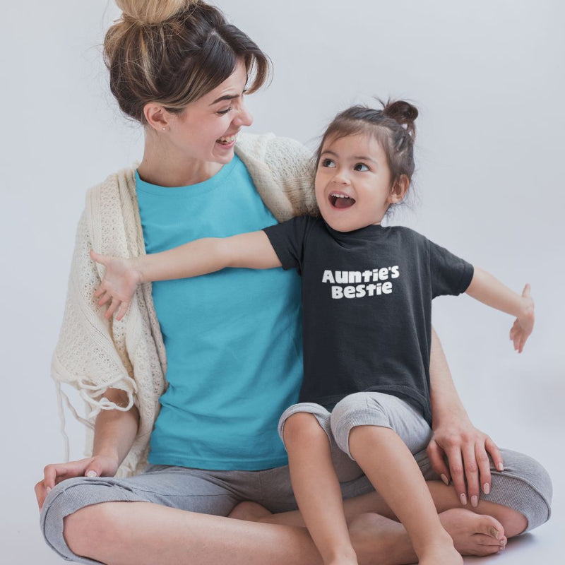 Woman and child sitting together, child wearing a black 'Auntie's Bestie' t-shirt by Less Hustle, More Joy.