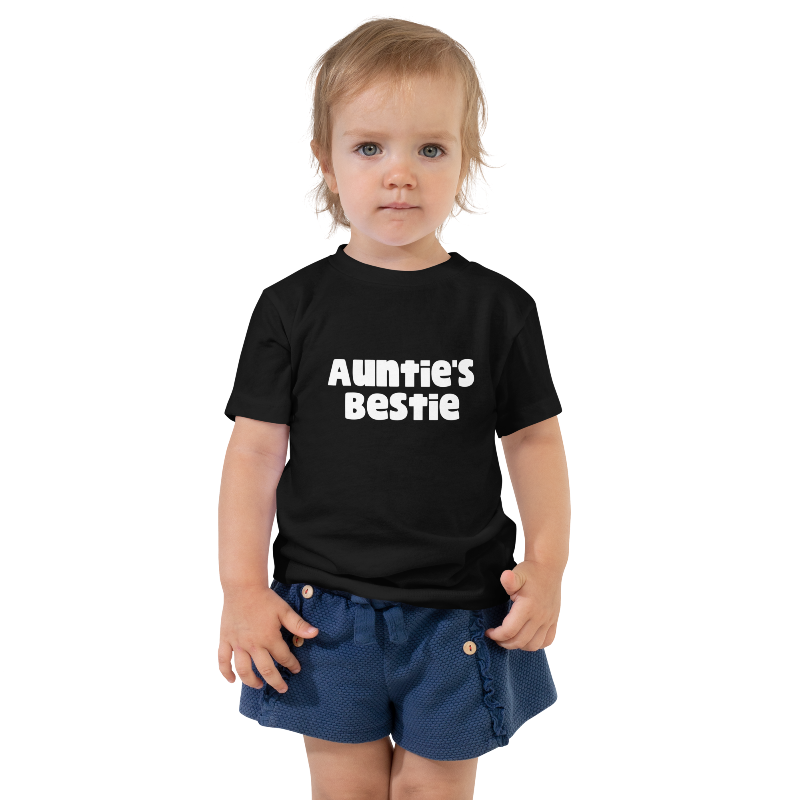 A child wearing a black t-shirt with white text that reads 'Auntie's Bestie'. By Less Hustle, More Joy.