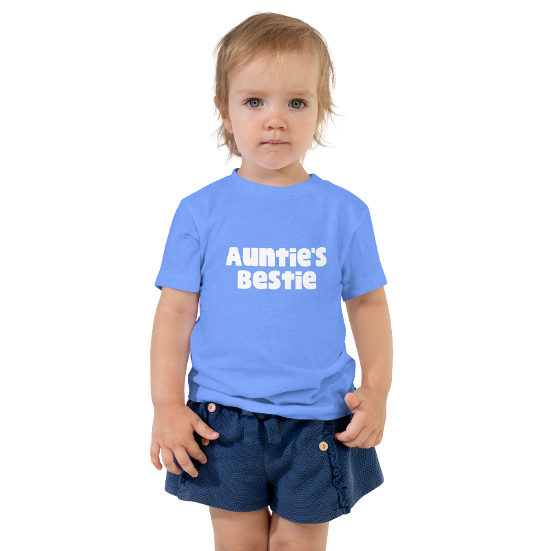 A child wearing a columbia blue t-shirt with white text on the front that reads 'Auntie's Bestie. By Less Hustle, More Joy.