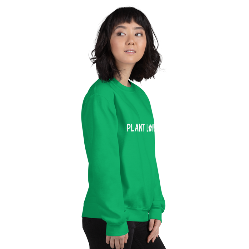 A person shown facing right, wearing an Irish green sweatshirt from Less Hustle, More Joy with the words 'PLANT LOVER' printed on the front in white text.