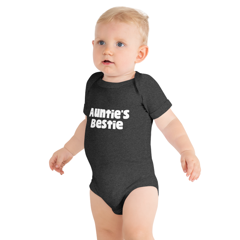 Baby wearing a dark, grey heather onesie with 'Auntie's Bestie' text, on plain background by Less Hustle, More Joy.
