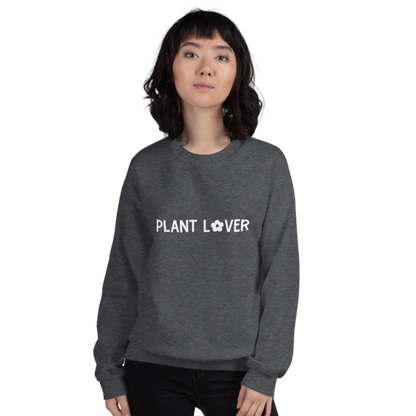 A person wearing a dark grey heather sweatshirt from Less Hustle, More Joy with the text 'PLANT LOVER' on the front in white.