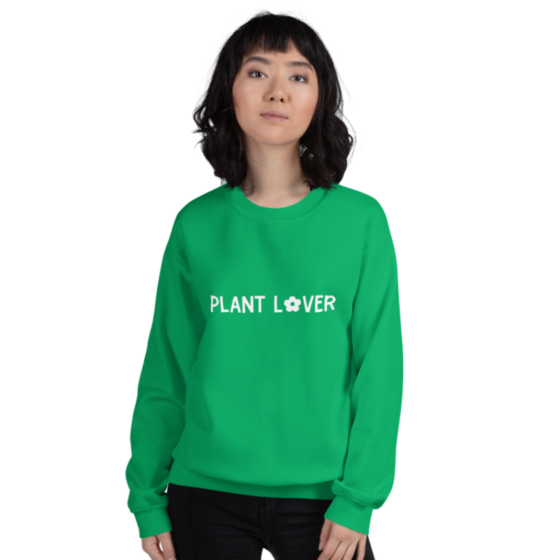 A person wearing an Irish green sweatshirt from Less Hustle, More Joy with the words 'PLANT LOVER' printed on the front in white text.