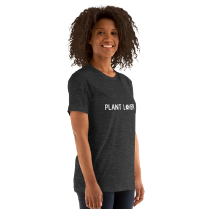 A person shown from the side wearing a dark grey heather t-shirt by Less Hustle, More Joy, with the words 'PLANT LOVER' printed on the front in white text.