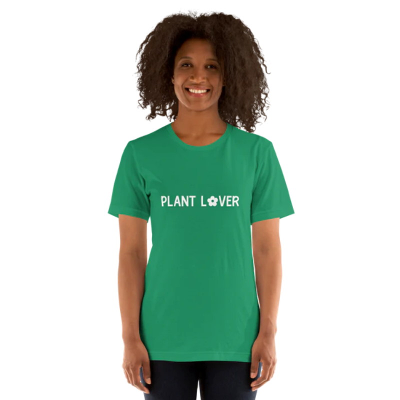 A person wearing a kelly green heather t-shirt by Less Hustle, More Joy, with the words 'PLANT LOVER' printed on the front in white text.
